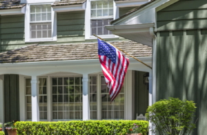 American flag waving in front of a typical american house.