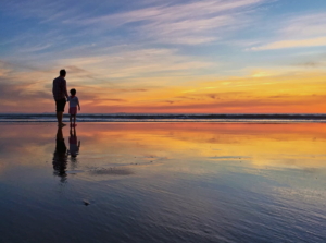 Sunset at low tide with father and child.