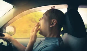 Sleepy yawning man driving car in traffic after long hour drive. Man falling asleep in car.
