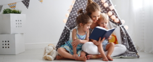 family mother reading to children book in tent in playroom at home