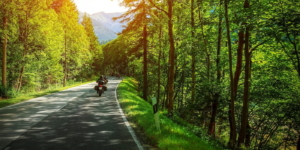 Biker on mountainous road in sunset light, motorcyclist on highway.