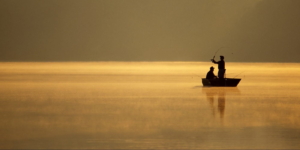 Two men fishing on a small boat.
