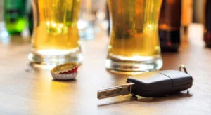 Drinking and driving concept. Car key on a wooden table, pub background