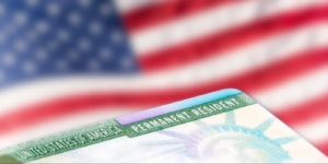 United States of America permanent resident cards, green card, with US flag in the background.