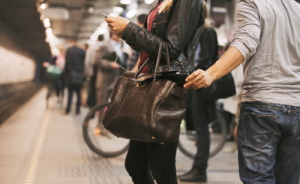 Young woman using mobile phone being robbed by a pickpocket at the subway station. Pickpocketing at subway station