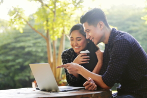 Happy asian couple looking at something on a laptop in outdoors