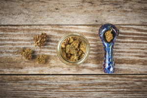 a pipe and glass jar with medical marijuana on a wood table