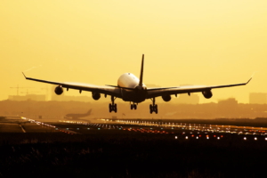 Airplane taking off at sunrise, yellow background.