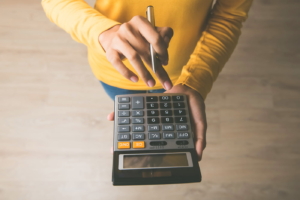Woman in yellow using a calculator to find the cost of divorce.