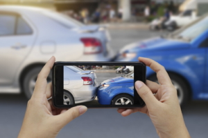 Close up hand holding smartphone and taking photos of a car accident. Collecting evidence.