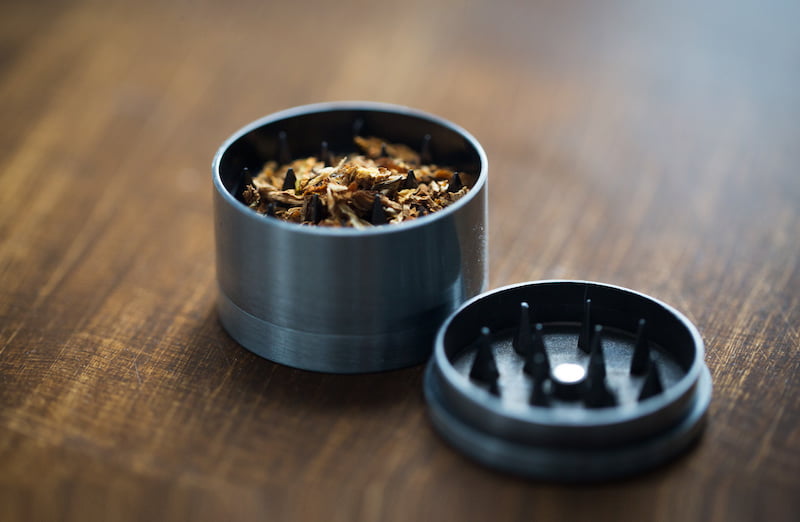 drug use, substance abuse, addiction and smoking concept - close up of marijuana or tobacco and herb grinder