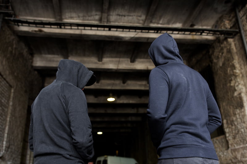 men in hoodies walking towards van in building.
