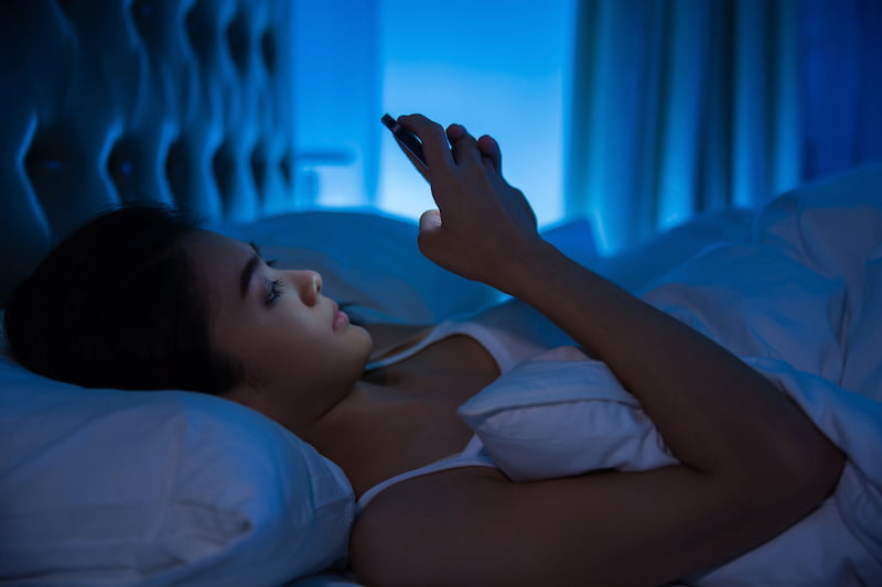 asian woman using her phone in bed.