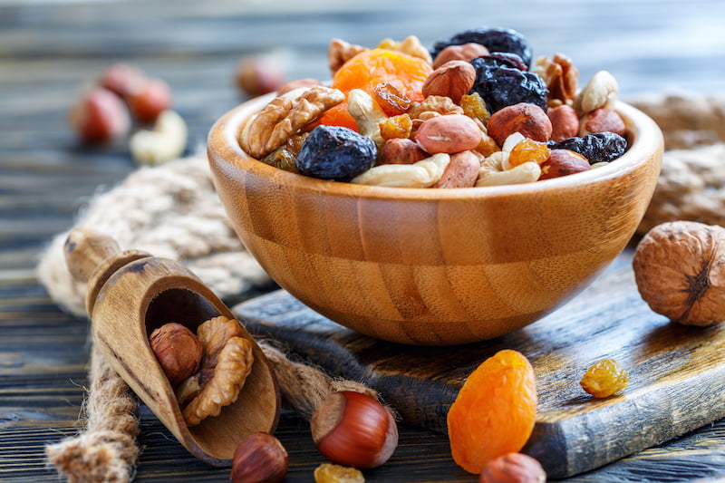 bowl of nuts and dried fruits and wooden scoop on the old table.