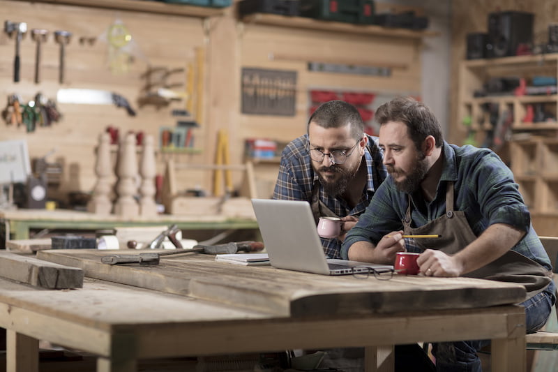 woodworkers using laptop on work bench.