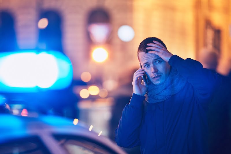 young man calling after a crisis situation on city street. 