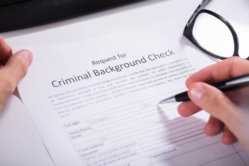 close-up of person hand filling criminal background check application form