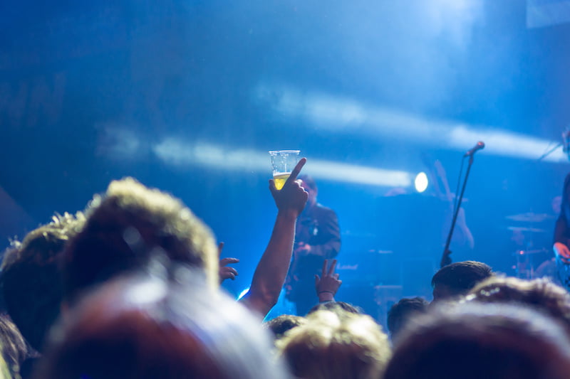 raised beer glass at a concert. consuming alcohol at music event.