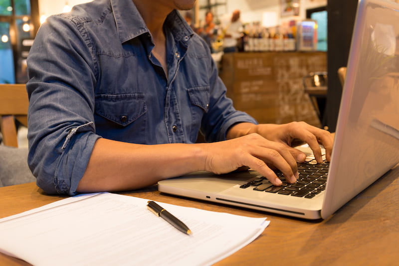 young casual man working on laptop in cafe at night