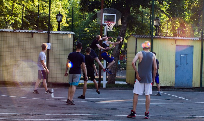 teens playing basketball in park.