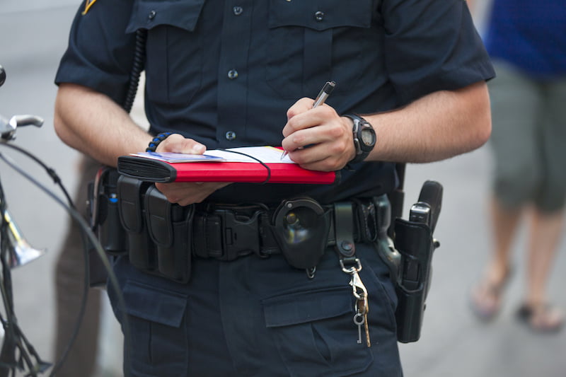 police officer writing a ticket on red binder.