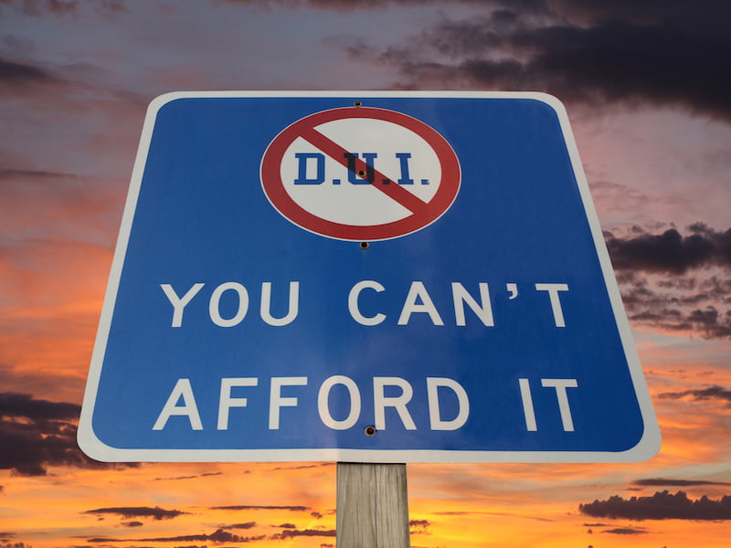 dui you can't afford it warning sign with sunset sky.