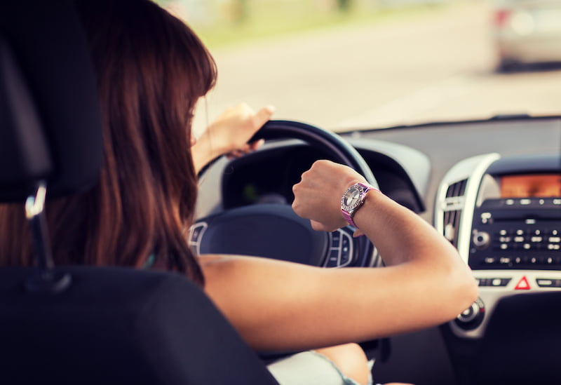 woman driving a car and looking at watch