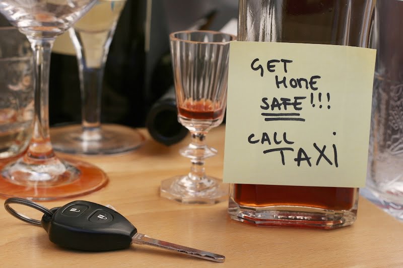 car keys on the table full of empty glasses, bottles at party, don't drink and drive concept, post it note for taxi