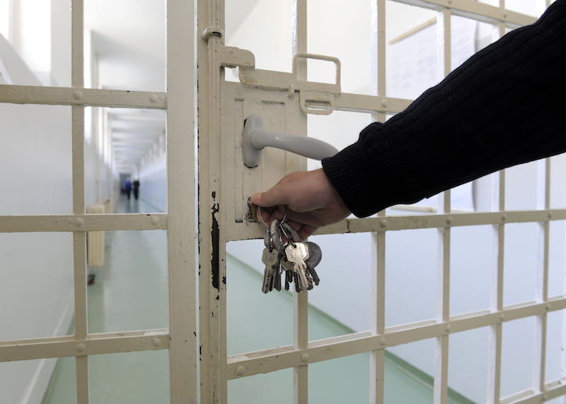 guard putting keys into door in prison.
