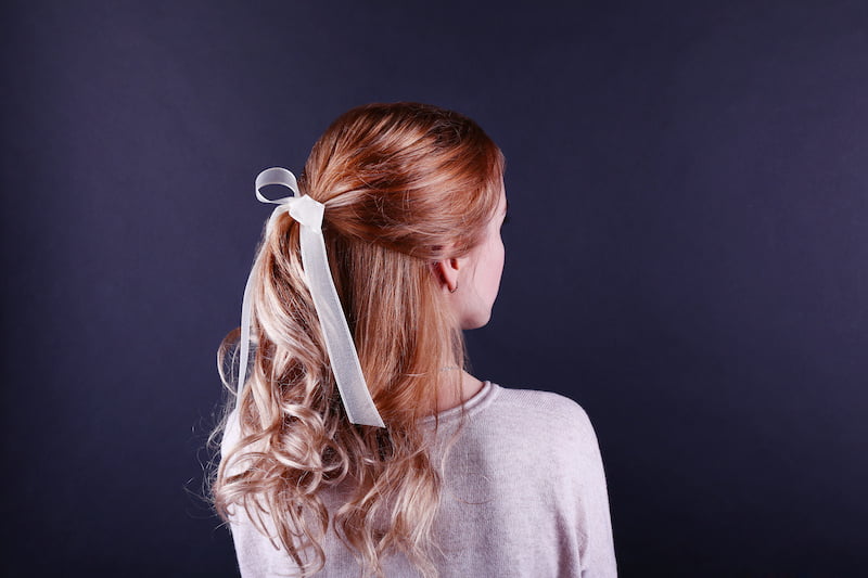 female hairstyle with color ribbon on dark background