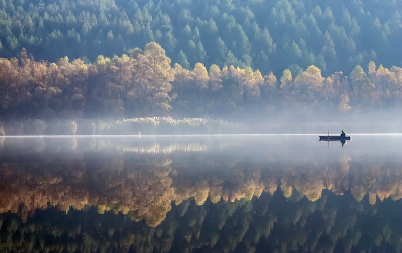 one angler fishing on a misty lake.