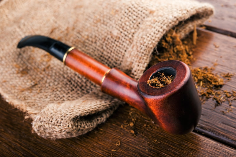 smoking pipe and tobacco on brown wooden table.
