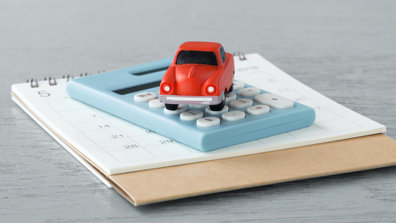 toy car on calculator and calendar on wooden table