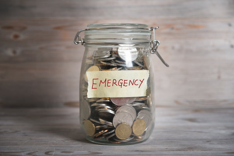 coins in glass money jar with emergency label, financial concept. vintage wooden background with dramatic light.