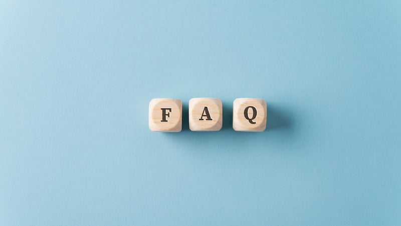 three wooden dices spelling faq over light blue background.