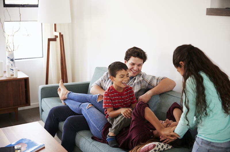 family having fun lying on sofa at home together