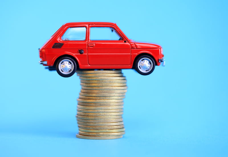 red miniature car on coin stack, insurance settlement concept.