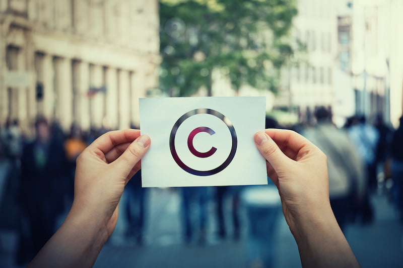 man holding up a piece of paper with the copyright symbol on it international copyright concept