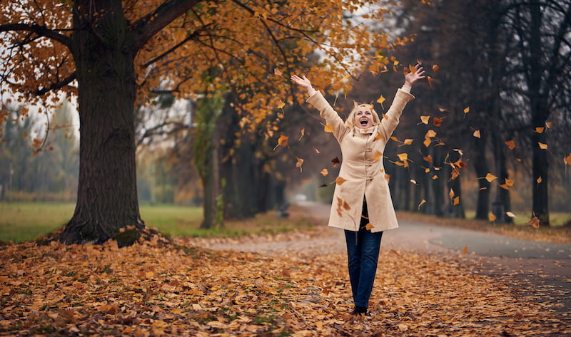 attractive senior woman is walking in park in autumn.