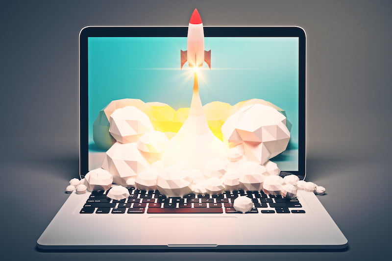 startup concept with rocket flying out of laptop screen on grey background.