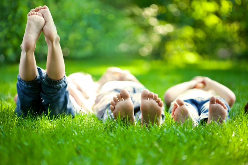 group of happy children lying on green grass outdoors in spring park