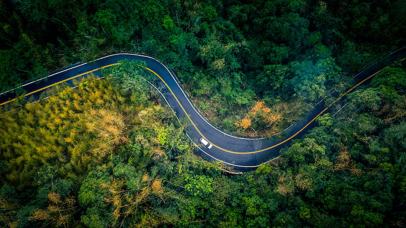 car in rural road in deep rain forest with green tree forest, aerial view car in the forest.