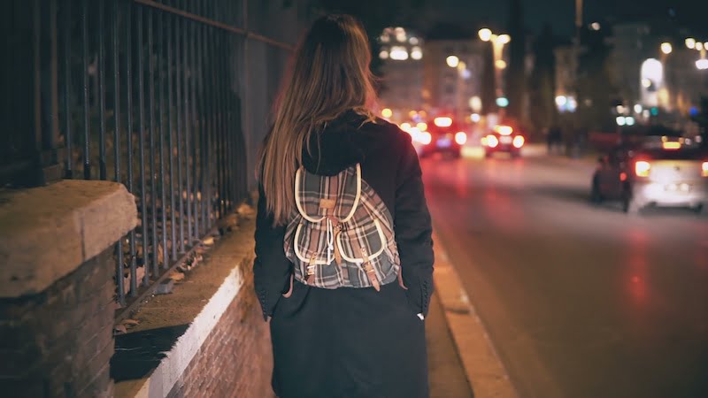 brunette woman with backpack walking late at night.