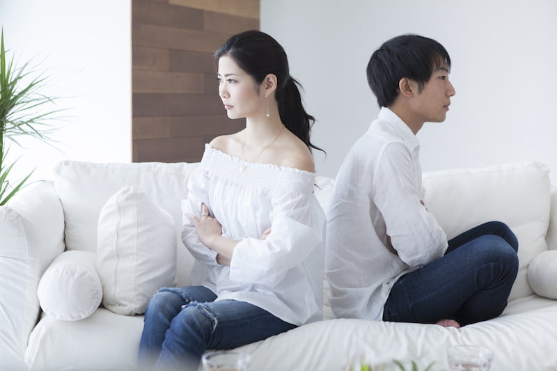 young couple has turned their backs to each other sitting on the sofa