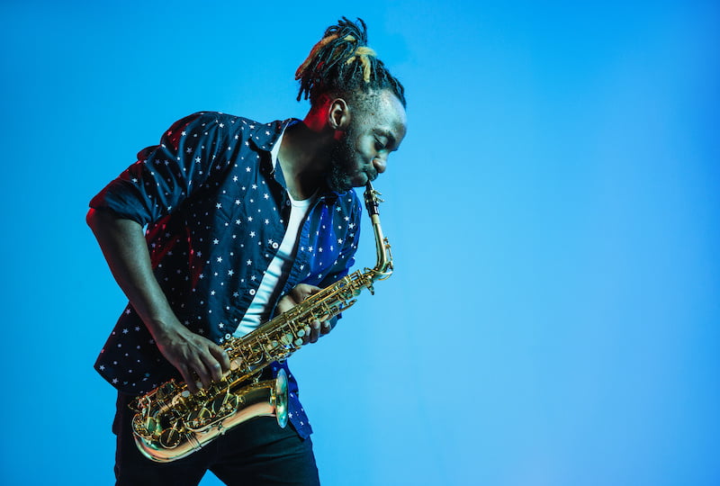 jazz musician playing the saxophone on a blue background.